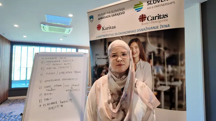 A workshop participant beside a flipchart and the EmpowerHER banner