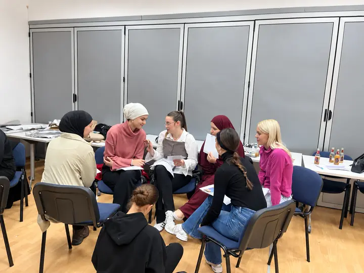 Women discussing printed materials together during a workshop